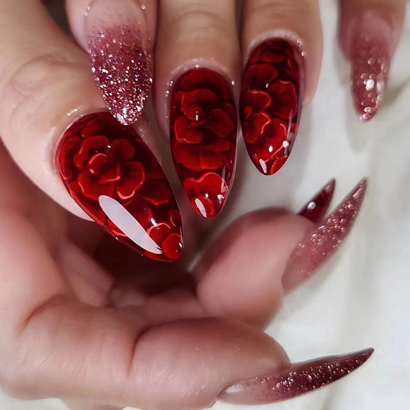 Uñas postizas con purpurina y forma de almendra con flores rojas
