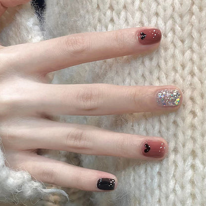 Uñas cortas con corazón negro y purpurina 