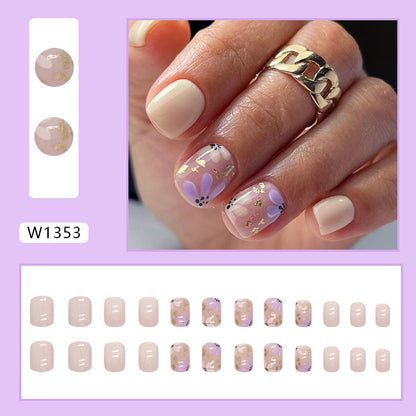 Uñas postizas cortas con purpurina y diseño floral en amarillo y morado 