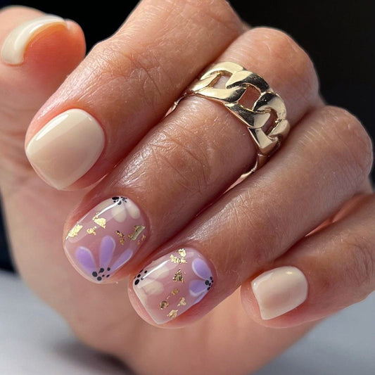 Uñas postizas cortas con purpurina y diseño floral en amarillo y morado 